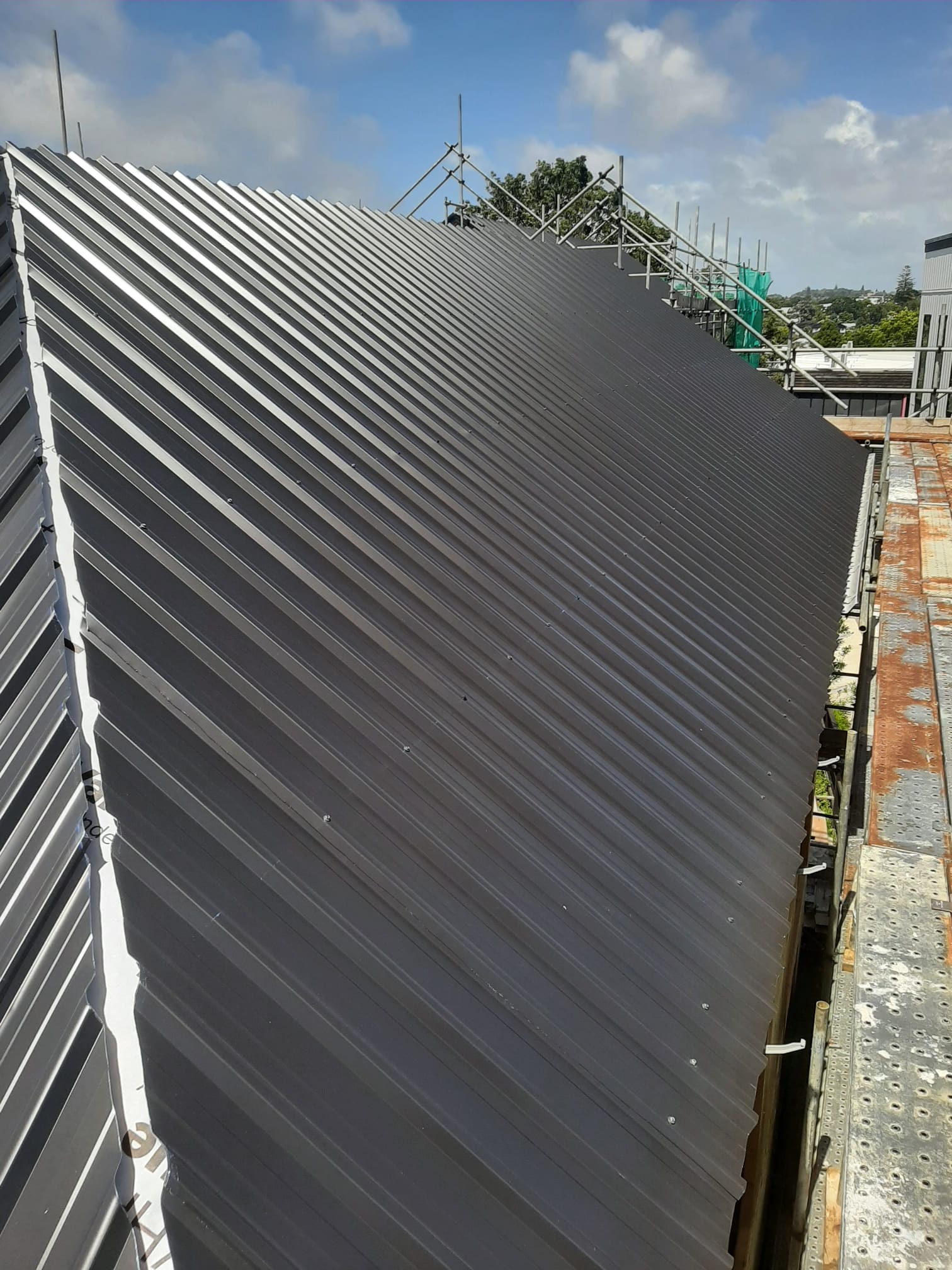 Dark charcoal Coloursteel longrun roof install on Auckland new build
