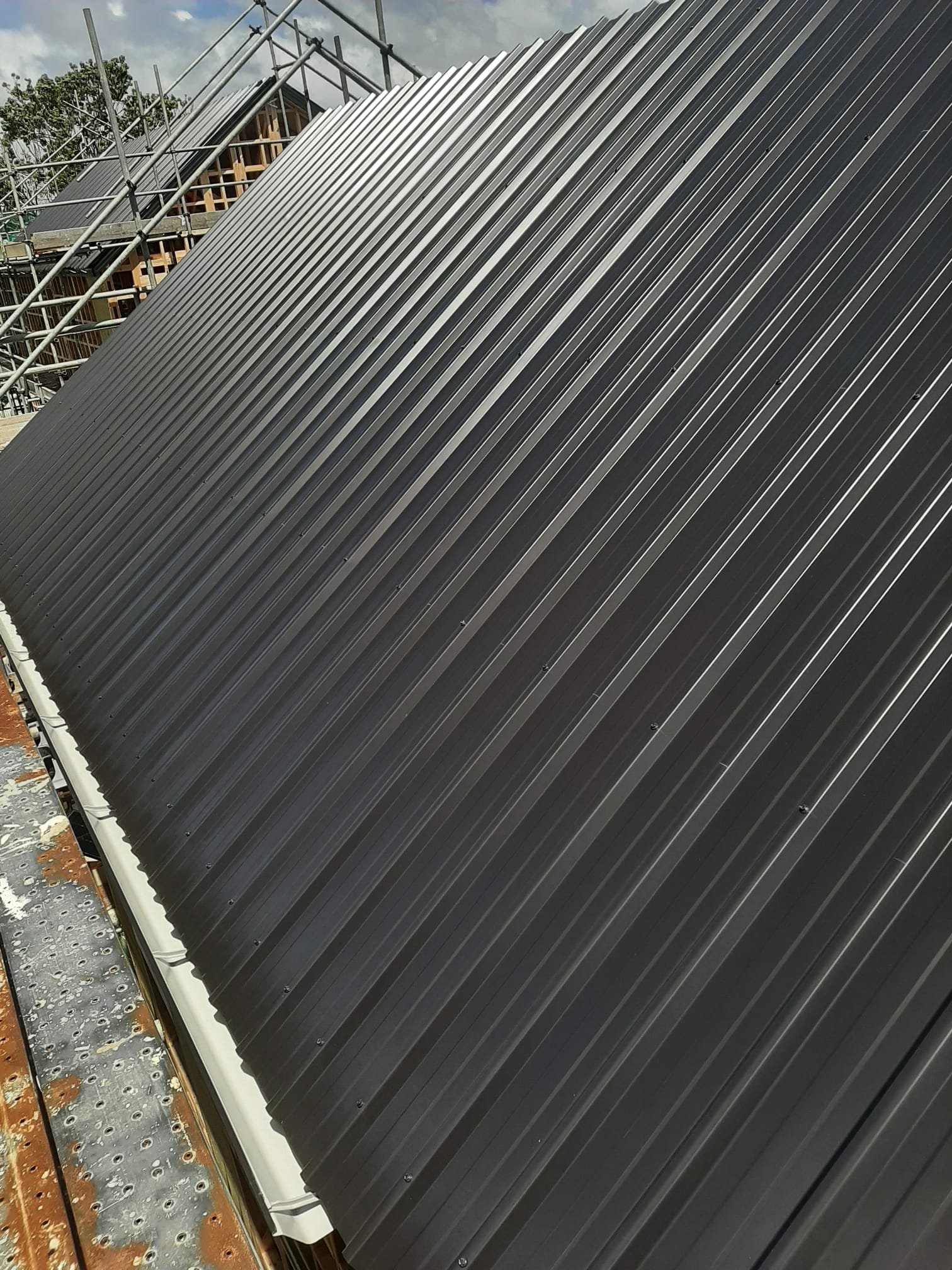Charcoal Coloursteel longrun roof from low angle with scaffolding â€” Auckland