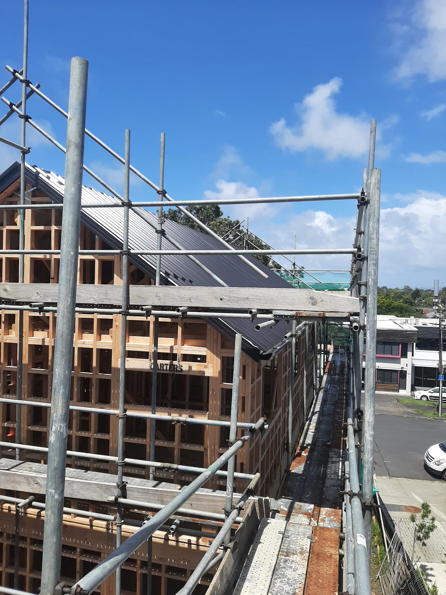 Scaffolded new build with Coloursteel roof install underway â€” Auckland
