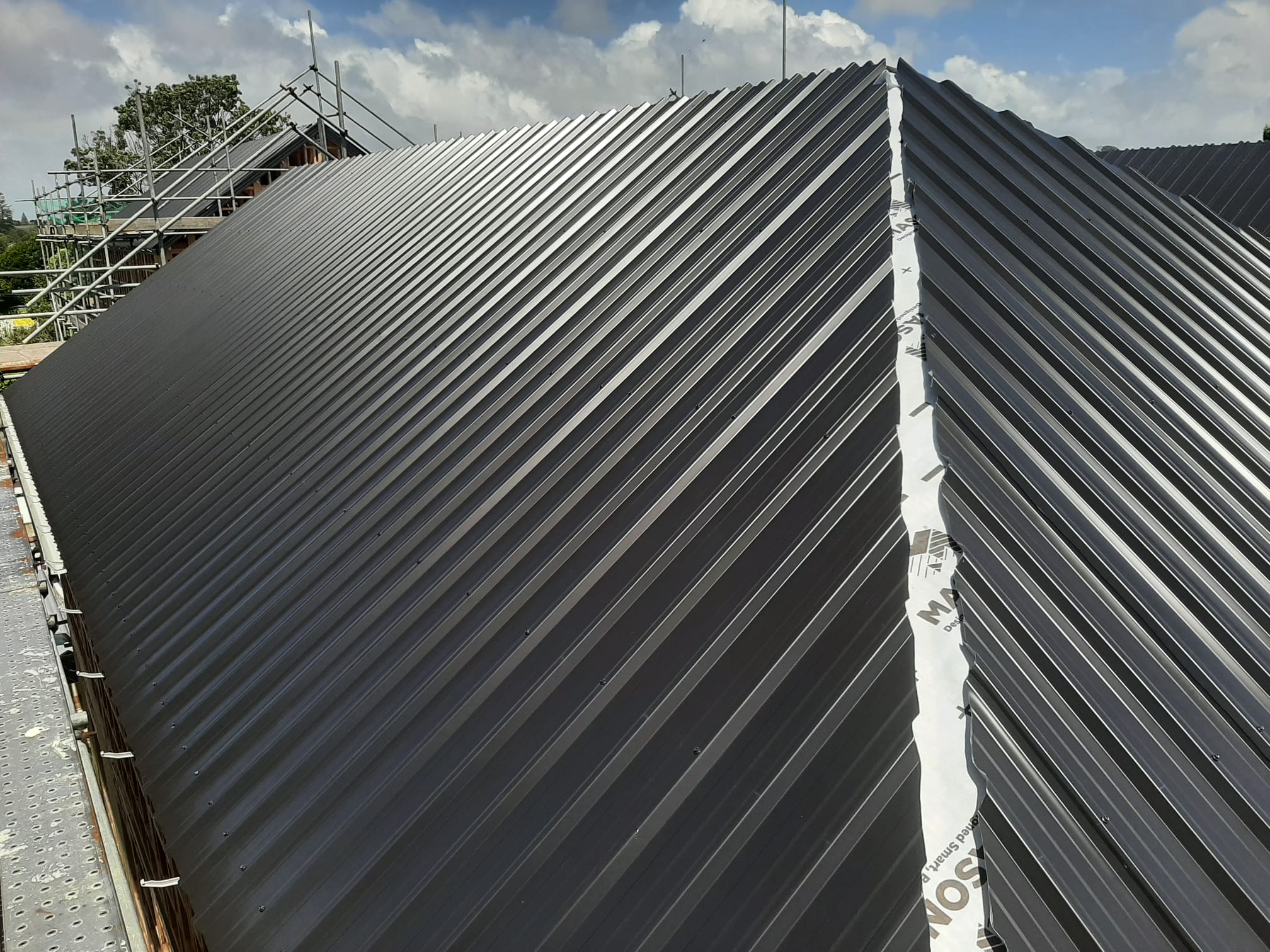 Dark Coloursteel main run with roof underlay visible at ridge â€” Auckland