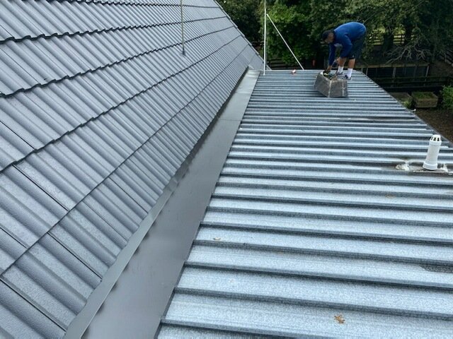 OneRoofing roofer working on a residential corrugated iron roof in Auckland